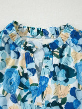Floral print short puff sleeve v neck blouse in blue and white with ruffled neckline and subtle stitching details