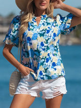 A floral print short blouse with puff sleeve v neck design in vibrant blue and green on cream background with ruffles