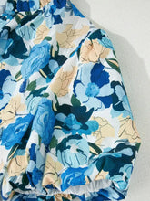 A flowing women’s skirt with a vibrant blue and beige floral print paired with a sleeve v neck blouse