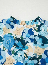 Women’s floral print short puff sleeve v neck blouse with vibrant blue and beige pattern and ruffled neckline detailing