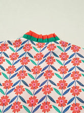 Floral print striped detail v neck ruffled short sleeve blouse with red and pink blossoms and contrasting orange green collar