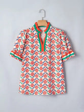 A vibrant coral and teal floral print neck ruffled short sleeve blouse with green and orange trim along the neckline
