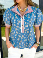 Blue floral print blouse with red and white striped trim button neck short sleeves and contrasting cuffs