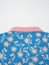 Blue blouse with white and gray floral pattern featuring a red and white striped trim button neck short sleeve design