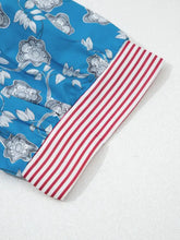 Blue shorts with gray floral pattern and red and white striped trim button cuffs complementing the button neck blouse