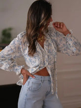 Delicate long sleeve blouse with tie neck featuring soft white base and subtle blue floral print for elegant wear