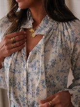 Gold coin pendant necklace with intricate detailing paired with a floral print long sleeve blouse with tie neck design