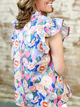 Vibrant floral print sleeveless top with ruffled shoulders high neckline featuring bold pink blue orange and green blossoms