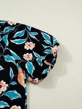 Black floral short bubble sleeve blouse with notched neck featuring turquoise leaves and peach flowers pattern