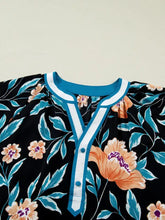 Black floral short bubble sleeve blouse with notched neck v-neckline and teal white trim featuring three buttons