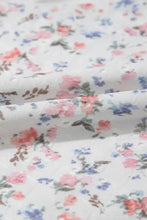 Floral textured square neck sleeveless bodysuit in white fabric with pink and blue blossoms and dark green leaves