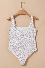 A white floral textured square neck one-piece swimsuit with delicate pink and blue patterns and thin straps
