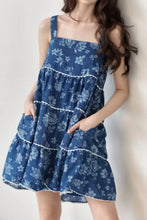 Blue floral print denim dress with tiered square neck and white lace trim along edges and pockets