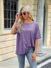 Woman in Florira round neck half sleeve purple t-shirt, blue jeans, sunglasses