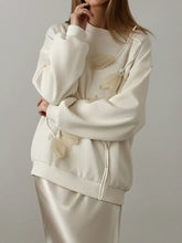Cream-colored flower dropped shoulder sweatshirt with sheer layered floral appliqués and matching drawstrings in oversized fit