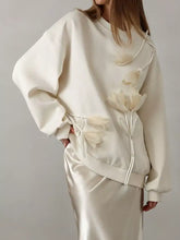 Cream-colored flower dropped shoulder sweatshirt with oversized fit and 3d floral appliqués and matching drawstring detailing