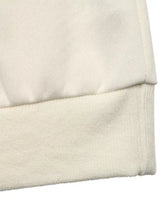 Cream-colored ribbed knit cuff detail on a flower dropped shoulder sweatshirt with soft textured fabric finish