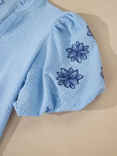Light blue waffle-knit dress with navy flower embroidered puff sleeves and a split neck textured blouse design