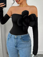Black off-the-shoulder long sleeve bodysuit with large three-dimensional floral embellishment on the right side