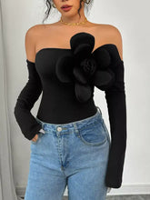 Black shoulder long sleeve bodysuit with off-shoulder design and large three-dimensional floral embellishment on chest
