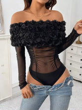 Black off-shoulder mesh bodysuit features sheer panels and ruffled rose embellishment across the bust
