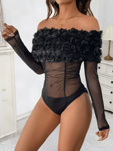 Black off-the-shoulder mesh bodysuit with sheer fabric and ruffled rose embellishment across the bust