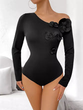 Black one shoulder long sleeve bodysuit featuring three-dimensional floral embellishments on the shoulder