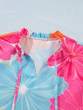 A sleeveless flower printed blouse with bold pink and blue floral patterns and a neck ruffle trim detail