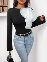Black ribbed flower round neck long sleeve bodysuit with large white sheer ruffled floral embellishment on shoulder