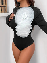 Black ribbed flower round neck long sleeve bodysuit with large white sheer ruffled floral embellishment on chest