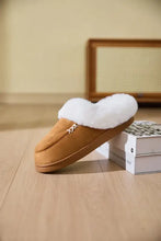 Tan fur-lined round toe flat slipper with white stitching and fluff trim