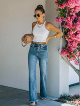 A tan leather handbag with a gold chain strap paired with frayed hem wide leg jeans