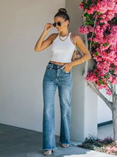 High-waisted blue denim wide leg jeans featuring a frayed hem for a stylish casual look