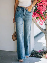 High-waisted medium-blue denim wide leg jeans with frayed hem and subtle distressing for a stylish look