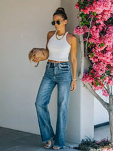 Tan leather handbag with gold chain strap paired with frayed hem high-waisted wide leg jeans