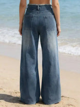 High-waisted frayed hem wide leg jeans in faded medium-blue denim with classic back pockets and distressed texture back view