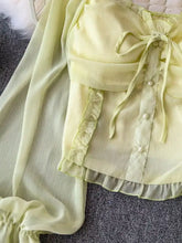 A delicate pale yellow sheer frill flounce sleeve blouse with ruffled trim and pearl buttons