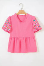 A vibrant pink frilled v neck flower embroidered puff sleeve textured blouse with ruffled trim at collar and hem