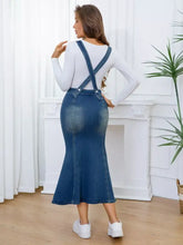 Blue denim overall dress with front buttons, crossed shoulder straps, fitted flared skirt, slightly stretchy, machine wash cold