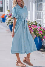 A light blue denim dress with buttons collared short bubble sleeves and a self-tie belt midi length design
