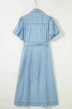 A light blue denim dress with full buttons collared short bubble sleeves and a matching belt