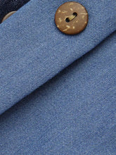 A round natural brown coconut button with rustic texture and two holes for sewing on full size button-front denim a-line skirt