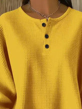Bright yellow waffle knit henley top with black buttons made of slightly stretchy material in plus size casual pullover style