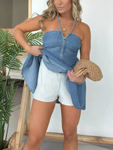 Blue denim halter neck mini dress plus size with front zipper and cross-over straps in a halter neck style