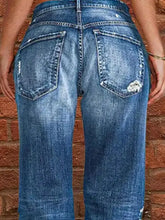 Blue denim full size distressed raw hem jeans showing back side with faded wash and distressed raw hem details on pockets
