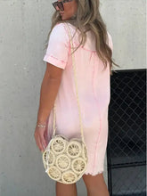 A round off-white woven handbag with a circular wheel-like pattern paired with a raw hem denim dress