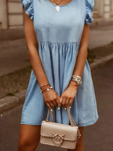 Beige leather crossbody bag with braided texture and heart-shaped clasp paired with full size ruffled round neck cap sleeve denim dress