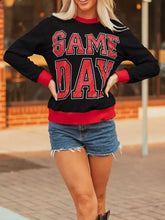 Black long sleeved slightly stretchy game day sweatshirt with red glitter lettering and machine wash cold care