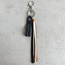 Genuine leather tassel keychain with embossed black strap and metallic accents
