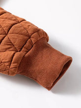 Warm rust-colored geometric quilted half zipped loose sweatshirt with ribbed cuff and machine wash care instructions